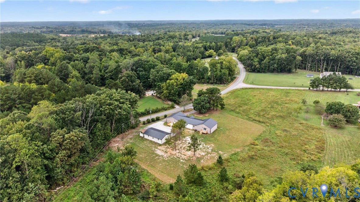 7621 Amelia Springs Road, Amelia, VA 23083 Expansive property featuring a curved asphalt road, multiple structures with dark roofing, and abundant surrounding trees