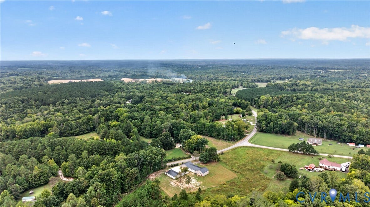 7621 Amelia Springs Road, Amelia, VA 23083 Expansive rural setting with abundant mature trees and a clear sky backdrop