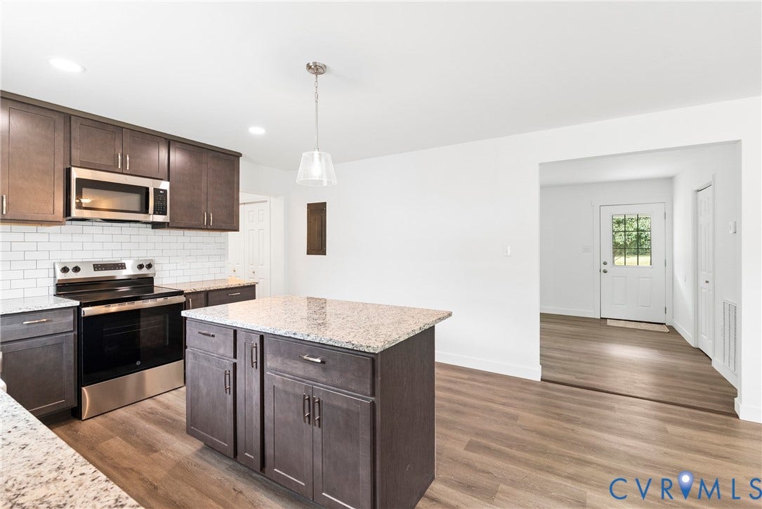 7621 Amelia Springs Road, Amelia, VA 23083 Kitchen featuring wood-finish flooring, dark wood cabinetry, light speckled countertops, subway tile backsplash, and stainless steel appliances