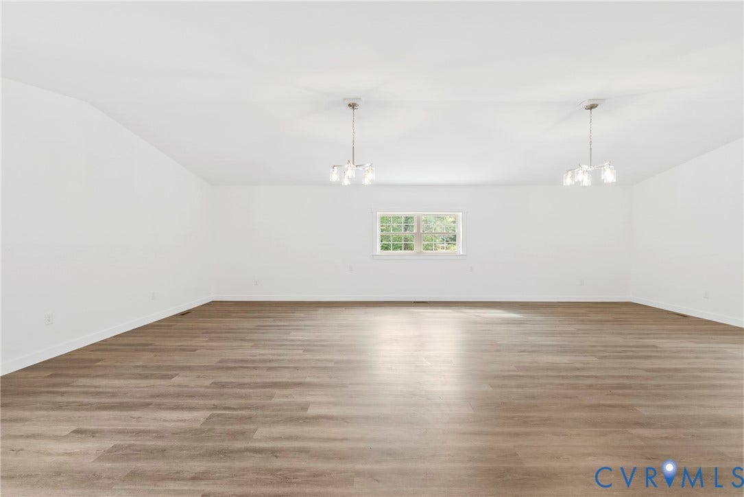 7621 Amelia Springs Road, Amelia, VA 23083 Spacious room featuring wood-finish flooring, white walls, two multi-light pendant fixtures, and a window providing natural illumination