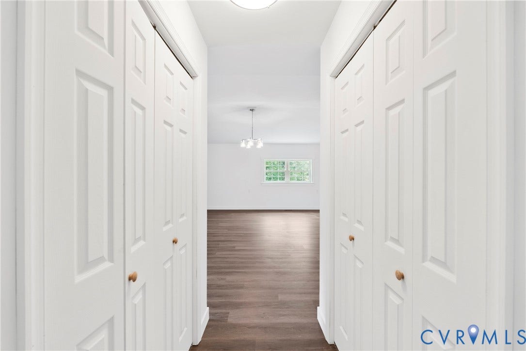 7621 Amelia Springs Road, Amelia, VA 23083 Hallway with multiple paneled bi-fold doors, wood-finish flooring, and white walls