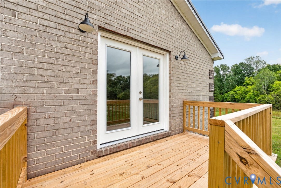 7621 Amelia Springs Road, Amelia, VA 23083 Exterior brick facade, wooden deck with railing, double glass doors, and two exterior wall lights