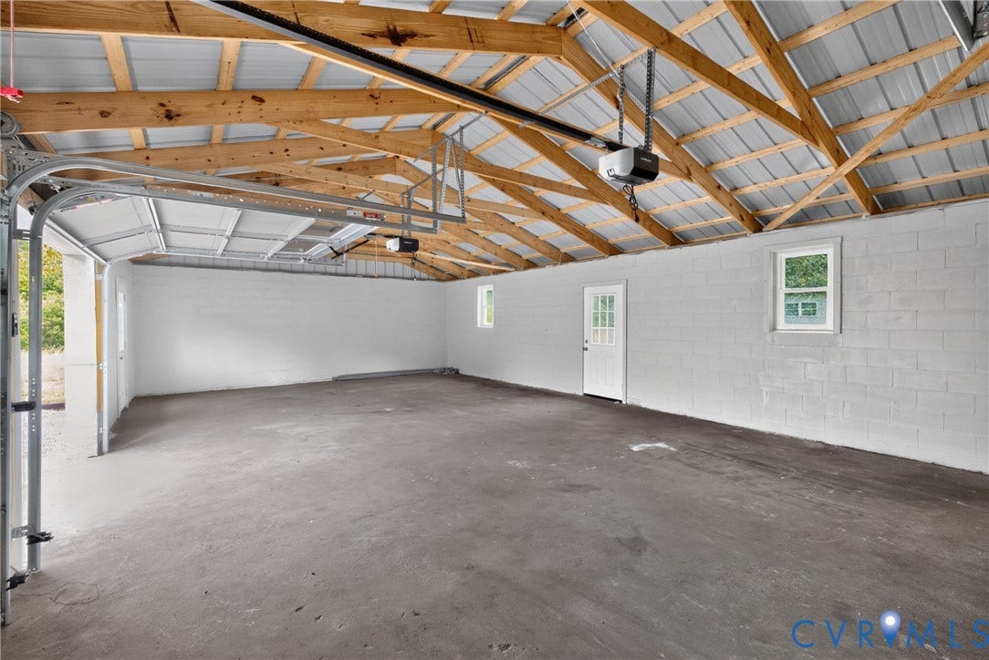 7621 Amelia Springs Road, Amelia, VA 23083 Spacious garage with exposed wood beam ceiling, corrugated metal roofing, concrete block walls, and concrete flooring