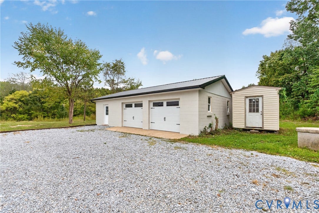 7621 Amelia Springs Road, Amelia, VA 23083 Two-car garage with white paneled doors, dedicated side entry, and a gravel driveway