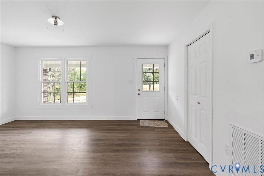 7621 Amelia Springs Road, Amelia, VA 23083 Wood-finish flooring, white walls, two double-hung windows with grids, a ceiling-mounted light fixture, and a white paneled door