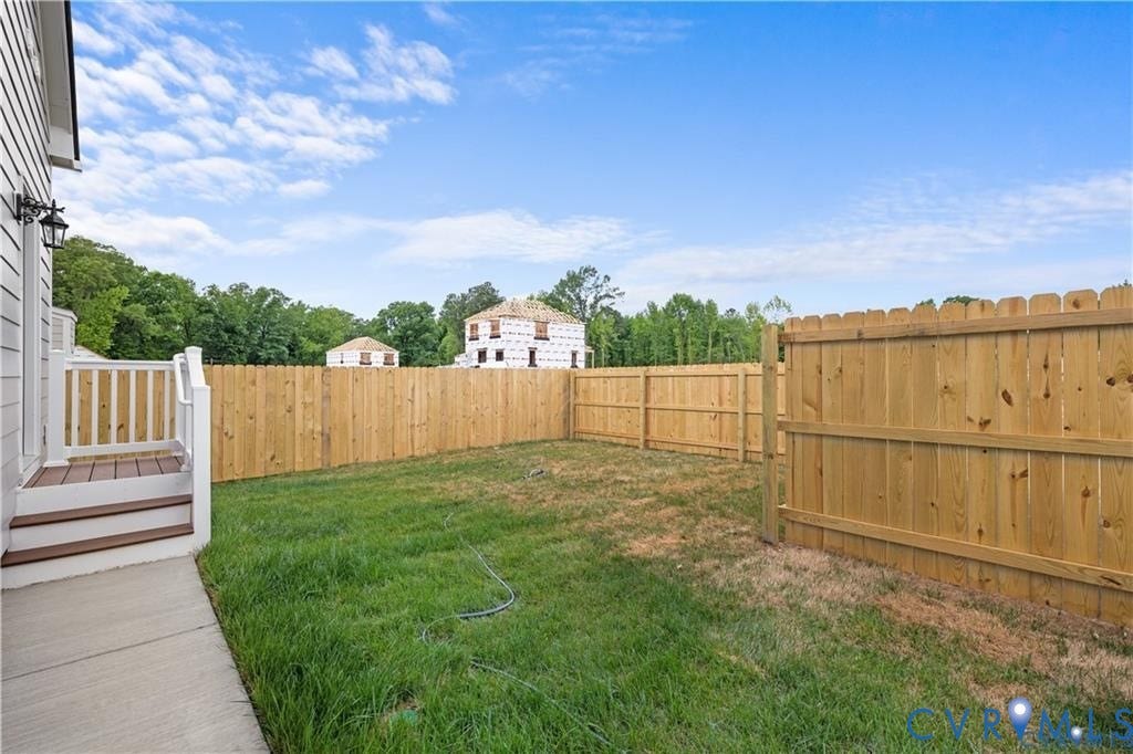 Private backyard featuring a wood privacy fence, green lawn, concrete patio, and a two-step deck with white railings