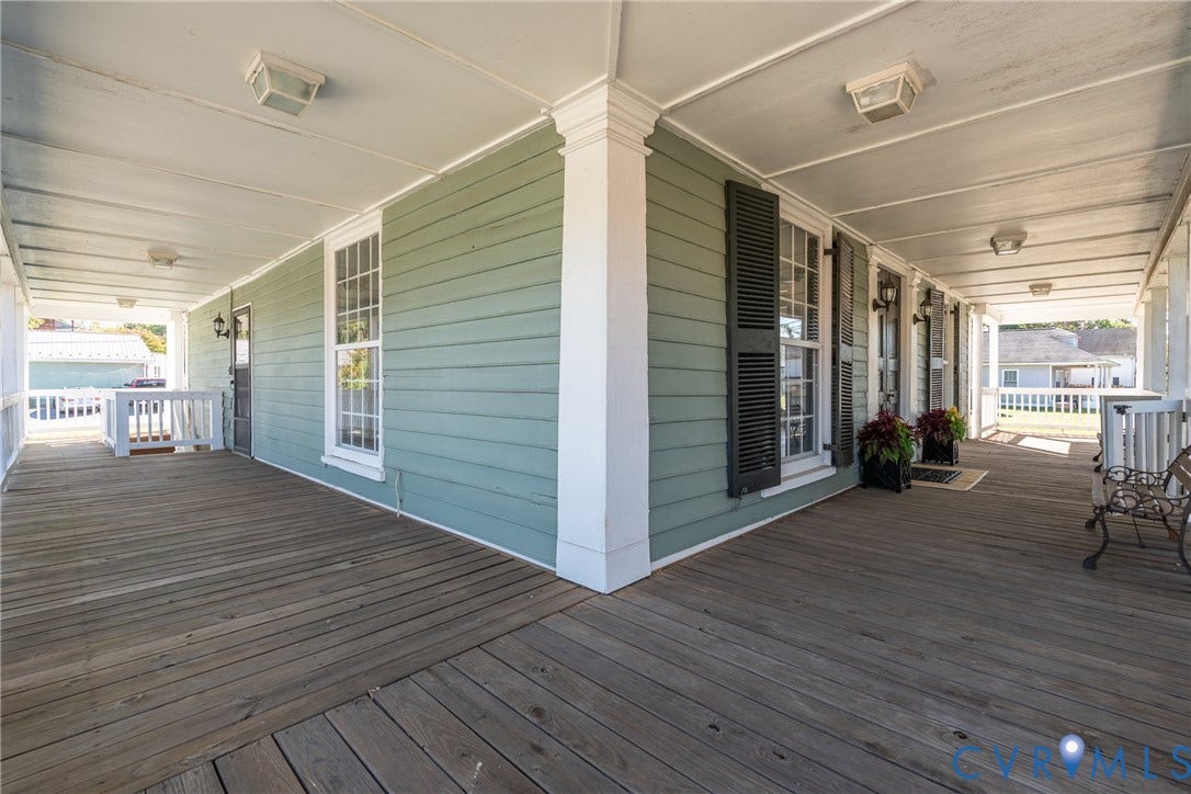 13085 W James Anderson Highway, Buckingham, VA 23921 Expansive covered porch featuring wood flooring, architectural columns, and exterior lighting fixtures