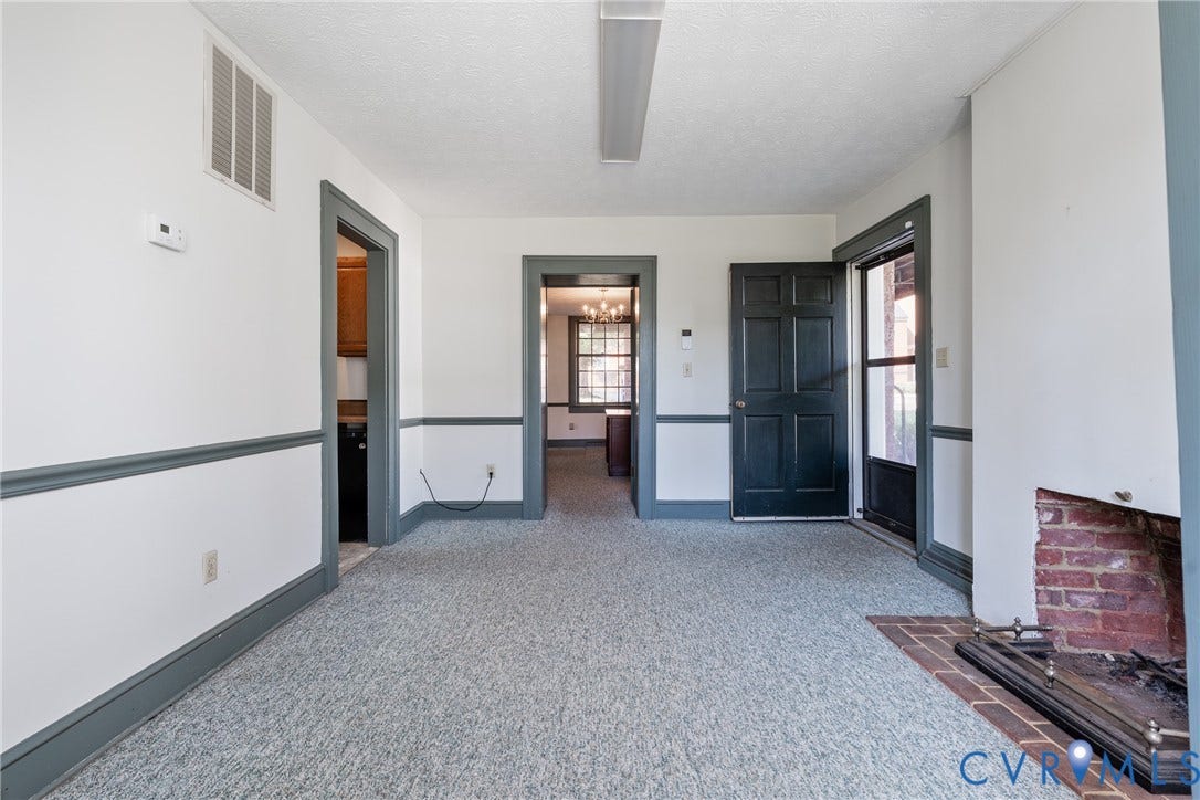 13085 W James Anderson Highway, Buckingham, VA 23921 Brick fireplace with metal grate, carpet flooring, paneled door, and two-tone wall treatment