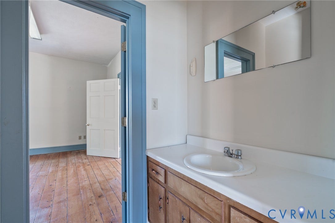 13085 W James Anderson Highway, Buckingham, VA 23921 Recessed oval sink with a two-handle faucet, wood-finish vanity with cabinet storage, and a wall-mounted mirror