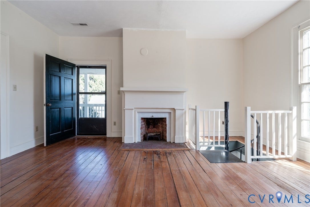 13085 W James Anderson Highway, Buckingham, VA 23921 Hardwood flooring, white fireplace with brick surround, white baluster railing, multi-pane window, and a paneled entry door