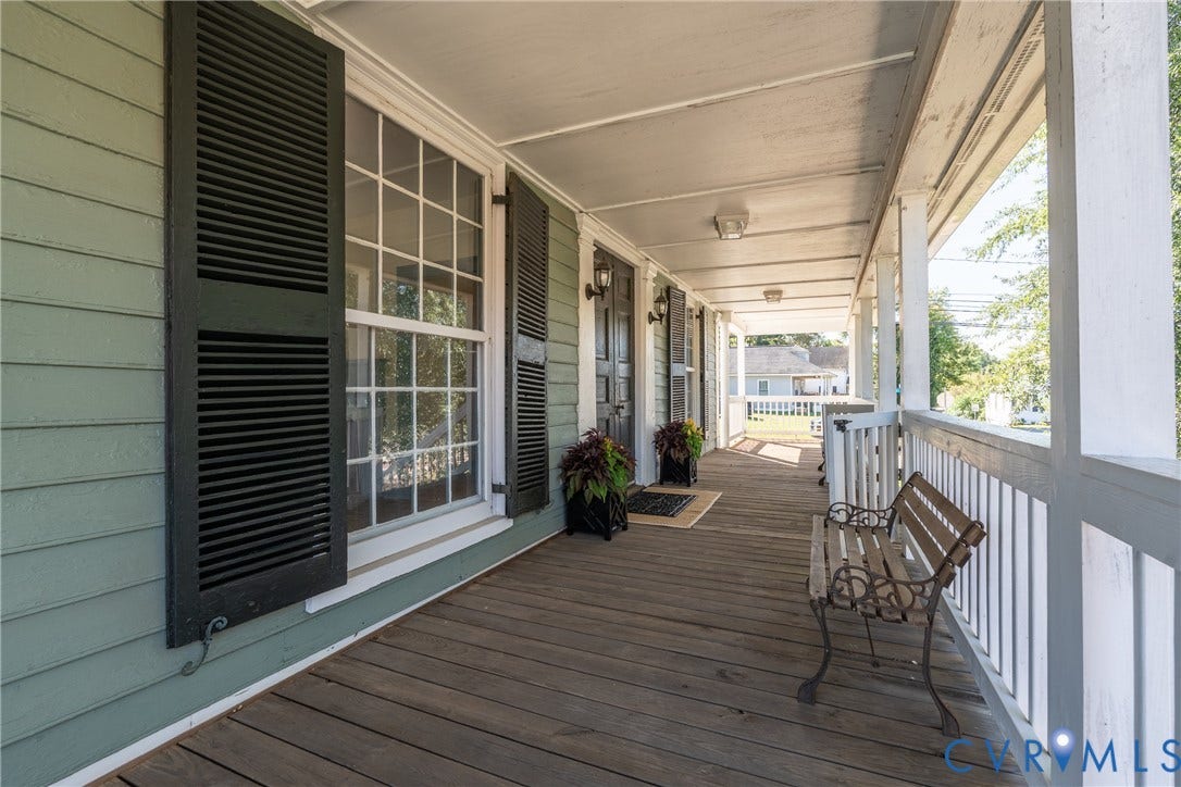 13085 W James Anderson Highway, Buckingham, VA 23921 Expansive covered porch featuring a wood-finish floor, white balusters, and a light green exterior with dark louvered shutters