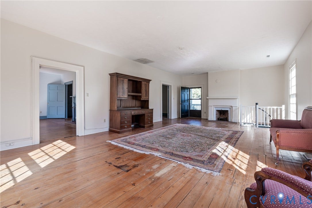 13085 W James Anderson Highway, Buckingham, VA 23921 Wood-finish flooring throughout, featuring a white painted fireplace with mantle, and a white painted staircase railing