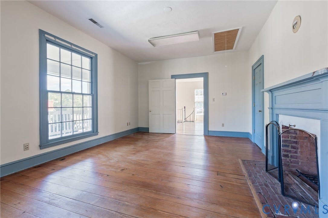 13085 W James Anderson Highway, Buckingham, VA 23921 Hardwood flooring, painted trim and door frames, prominent window with muntins, brick fireplace with mantel, and white interior doors