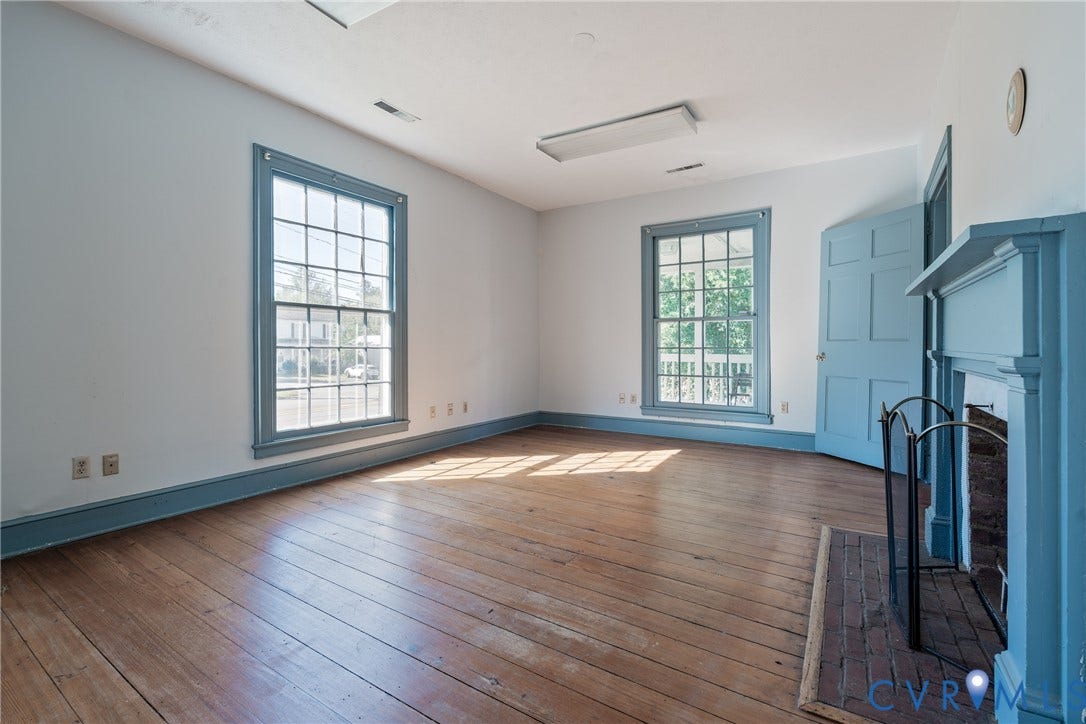 13085 W James Anderson Highway, Buckingham, VA 23921 Hardwood flooring, painted fireplace with brick hearth, two large multi-pane windows, painted five-panel door, and painted trim