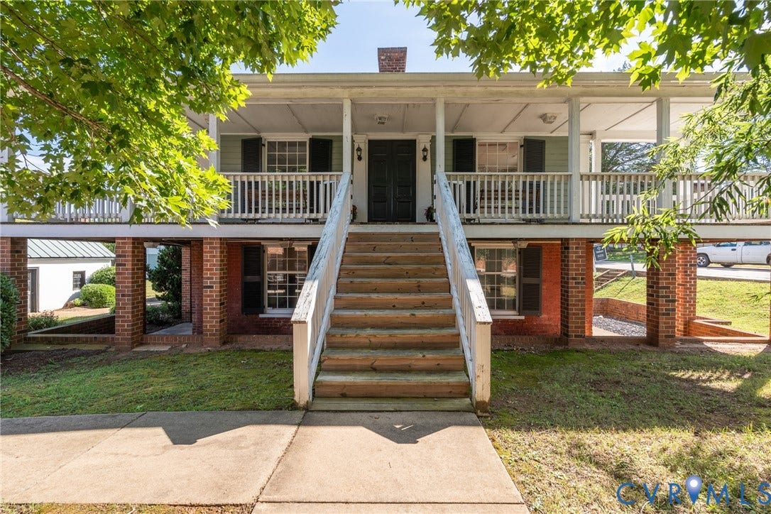 13085 W James Anderson Highway, Buckingham, VA 23921 Elevated classic-style residence featuring a wide front porch, multiple windows with dark shutters, and a prominent brick foundation