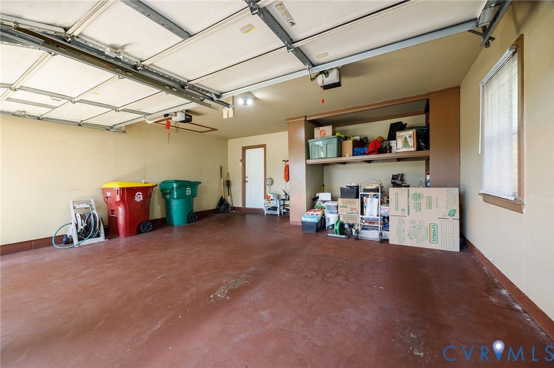 3356 Seaton Road, Petersburg, VA 23805 Spacious garage with overhead door, built-in shelving, and a window for natural light