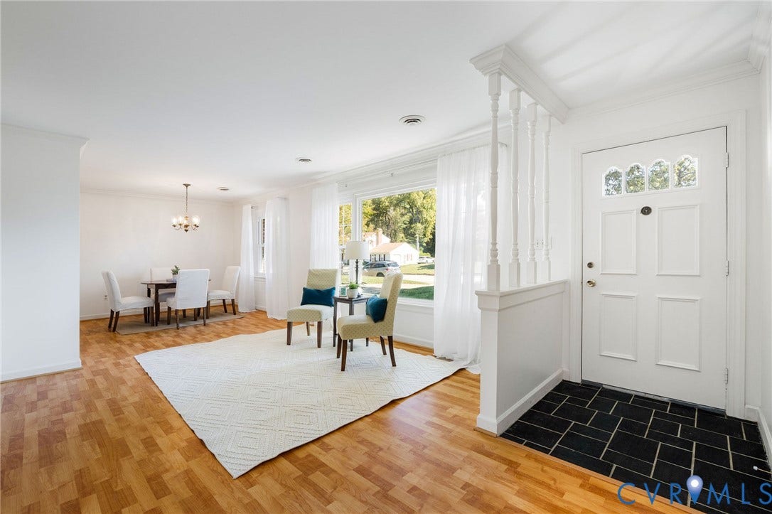 3356 Seaton Road, Petersburg, VA 23805 Wood-finish flooring, white paneled entry door with decorative glass, black tile entryway, crown molding, and a chandelier in the dining area
