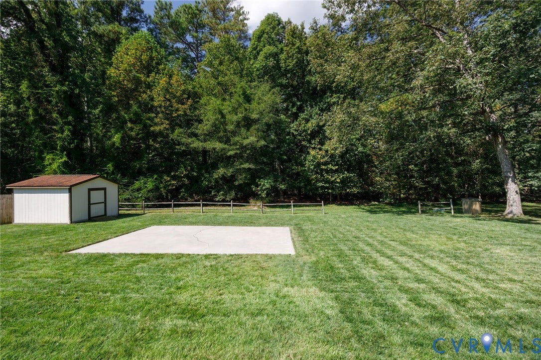 3356 Seaton Road, Petersburg, VA 23805 Expansive green lawn featuring a concrete patio, a storage shed with a brown roof, and a wood-post fence