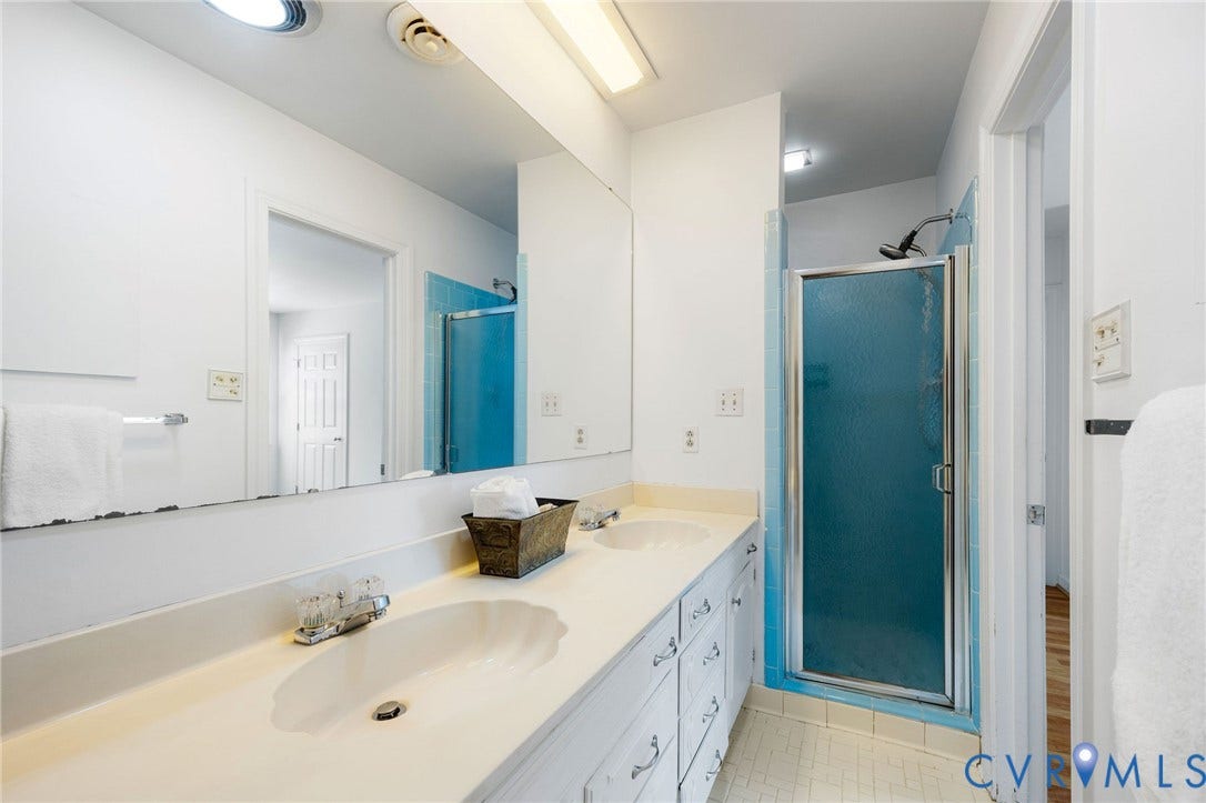 3356 Seaton Road, Petersburg, VA 23805 Dual vanity with integrated sinks, expansive wall-mounted mirror, and a standing shower with a frosted panel door