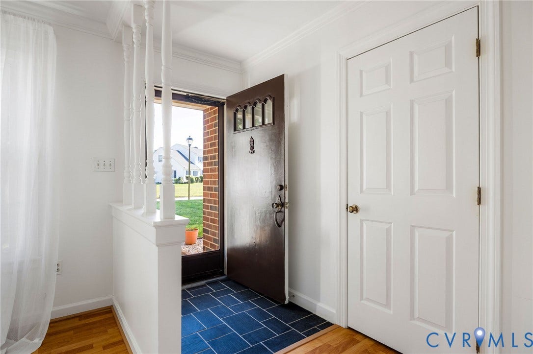 3356 Seaton Road, Petersburg, VA 23805 Entryway featuring a dark paneled door with decorative glass, blue tile flooring, wood-finish flooring, a white half-wall with spindles, and a white six-panel interior door