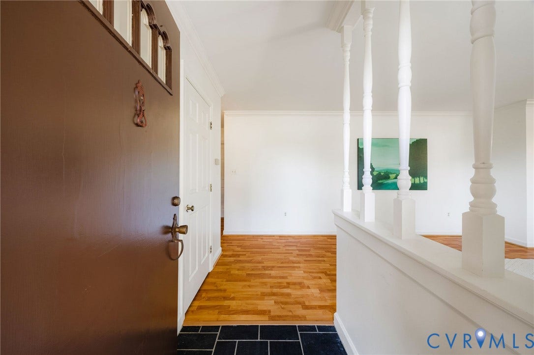 3356 Seaton Road, Petersburg, VA 23805 Entryway featuring a dark wood door with decorative transom window, black tile flooring, wood-finish flooring, and white railing with turned balusters