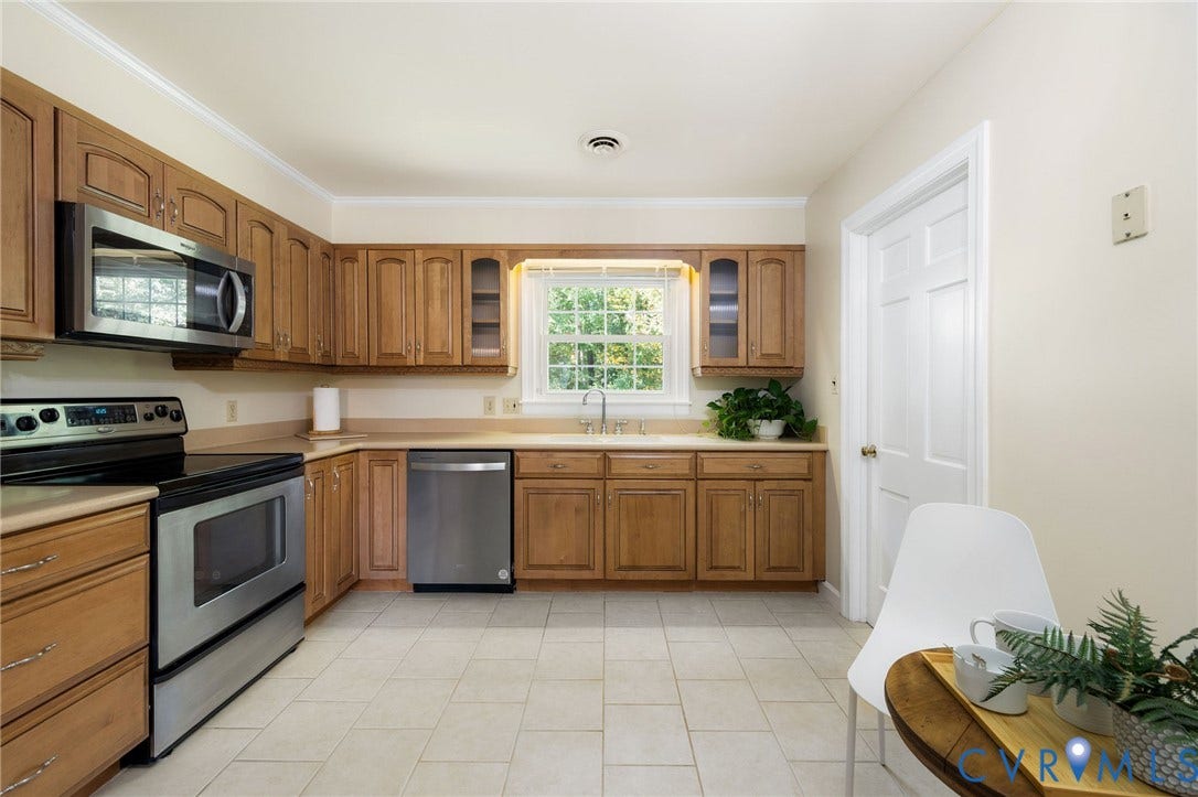 3356 Seaton Road, Petersburg, VA 23805 Kitchen featuring wood cabinetry, stainless steel appliances, a corner sink with a window, and tile flooring