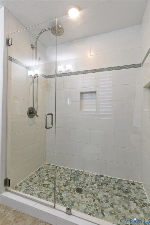4327 Wakefield Road, Stratford Hills, Richmond, VA 23235 Glass-enclosed shower with pebble-tile flooring, white subway tile walls, and a recessed niche