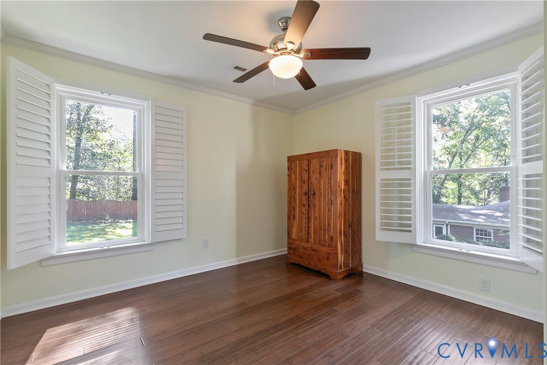 4327 Wakefield Road, Stratford Hills, Richmond, VA 23235 Wood-finish flooring, crown molding, ceiling fan with integrated lighting, and white plantation shutters on two windows