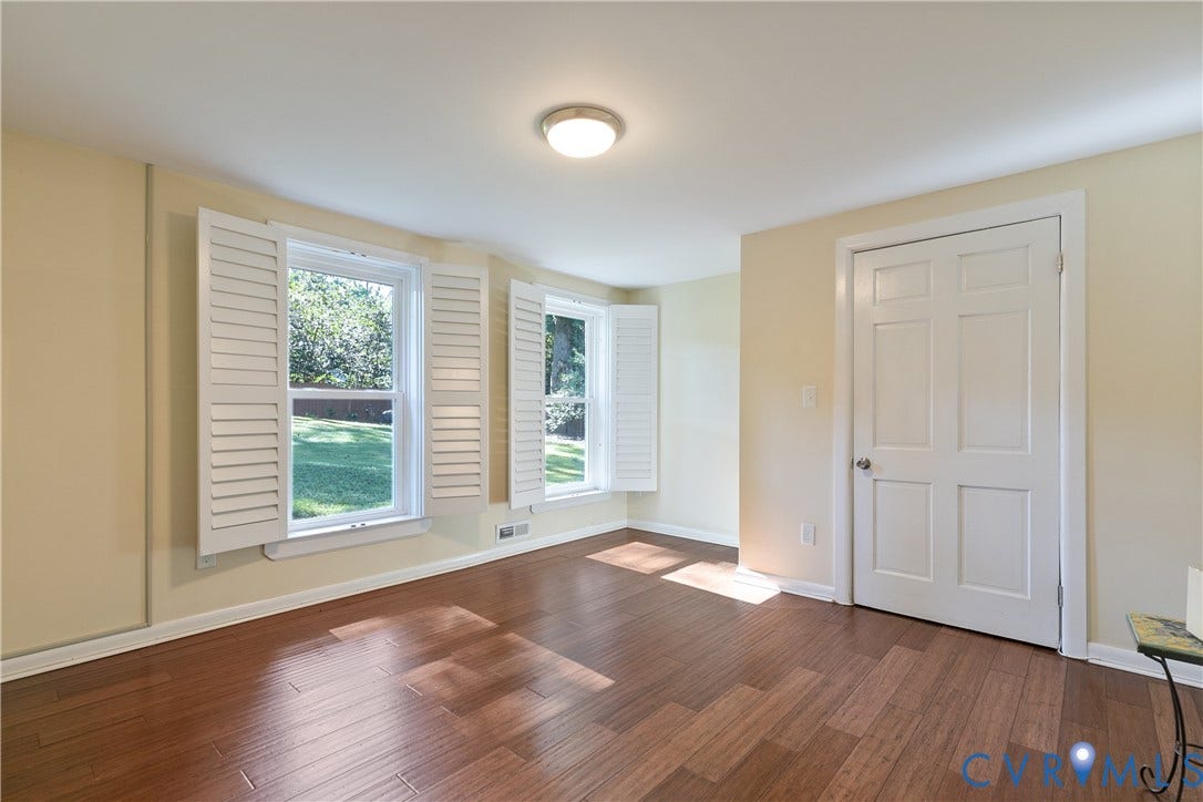 4327 Wakefield Road, Stratford Hills, Richmond, VA 23235 Hardwood-style flooring, multiple windows with white shutters, ceiling-mounted light fixture, and a six-panel interior door