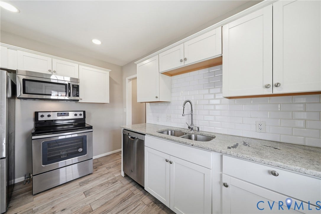 1718 Rogers, Richmond, VA 23223 Kitchen featuring white shaker-style cabinetry, stainless steel appliances, a white subway tile backsplash, light-toned countertops, and wood-finish flooring