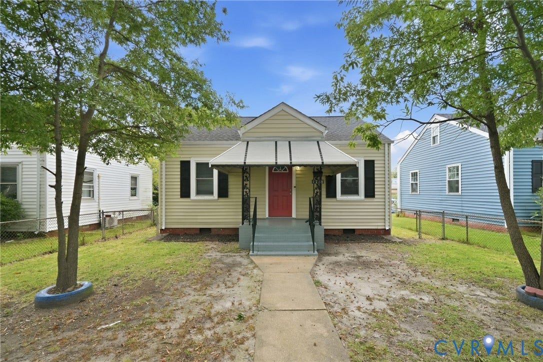 1718 Rogers, Richmond, VA 23223 Exterior featuring light yellow siding, a red entry door, decorative black shutters, a covered porch with an awning, and a gabled roof