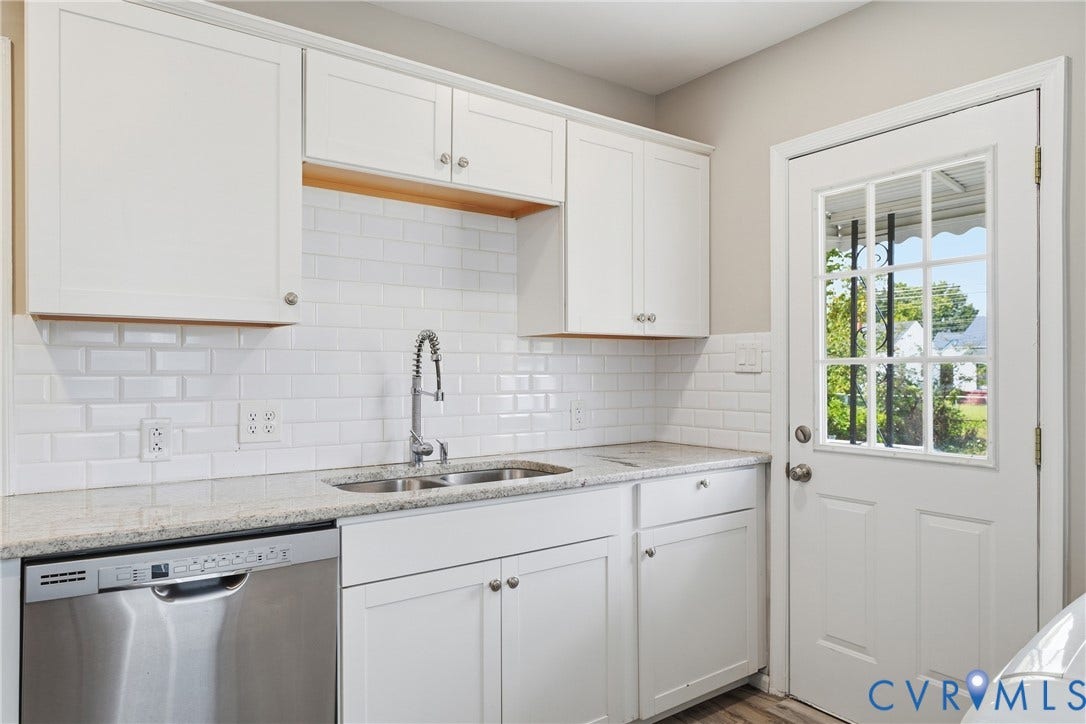 1718 Rogers, Richmond, VA 23223 White shaker-style cabinetry, stainless steel dishwasher, double basin sink with gooseneck faucet, light-toned countertop, and a white subway tile backsplash