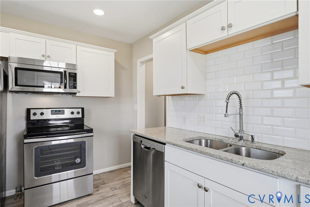 1718 Rogers, Richmond, VA 23223 Kitchen featuring stainless steel appliances, white cabinetry, a double basin sink, light-toned countertops, and wood-finish flooring