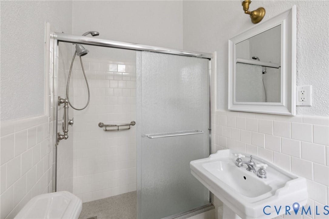First floor, white subway tile shower surround with a sliding glass door