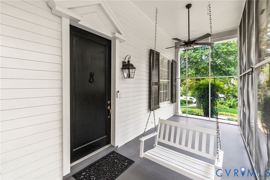 Screened porch featuring a ceiling fan, porch swing, and dark shutters