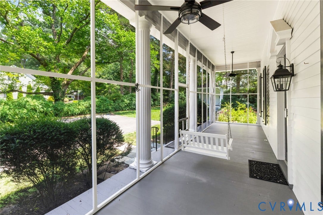 Screened-in porch featuring a porch swing, columnar architectural elements, two ceiling fans, and a wall-mounted lantern-style fixture