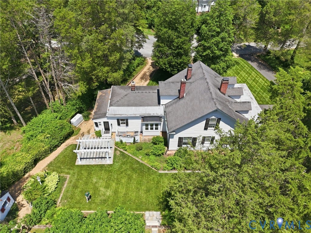 White siding exterior with multiple gabled rooflines, two brick chimneys, and black window shutters