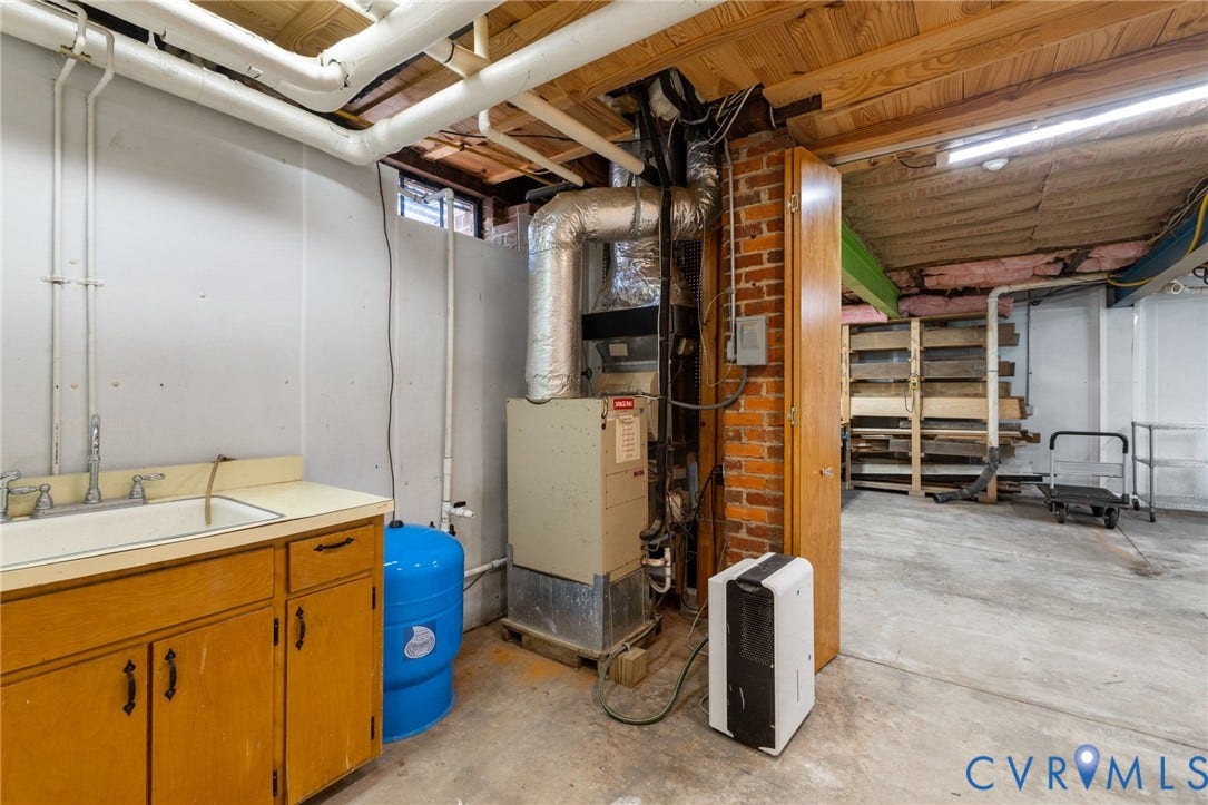 Utility area featuring a built-in sink with cabinetry, HVAC system, and exposed brickwork