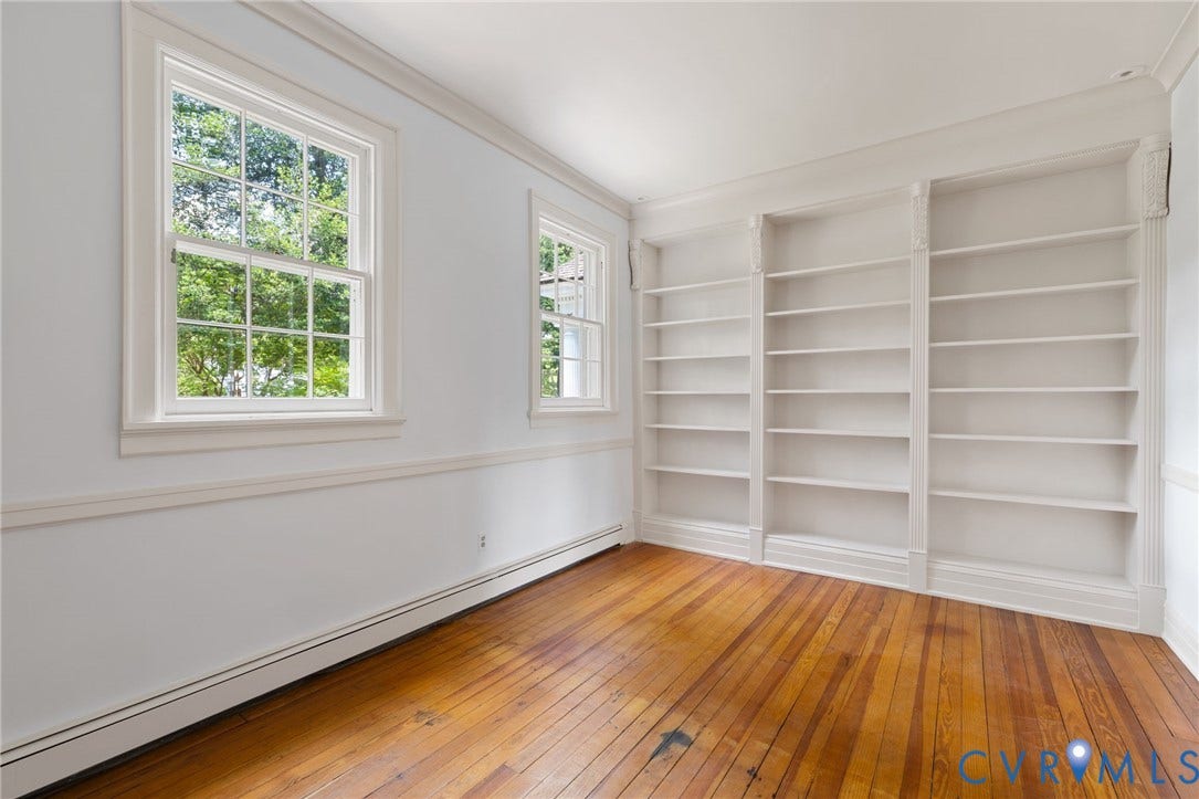 Hardwood flooring, two large windows, white trim, crown molding, and built-in shelving