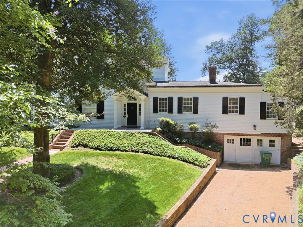 White siding exterior with black shutters, brick foundation, and a covered entry