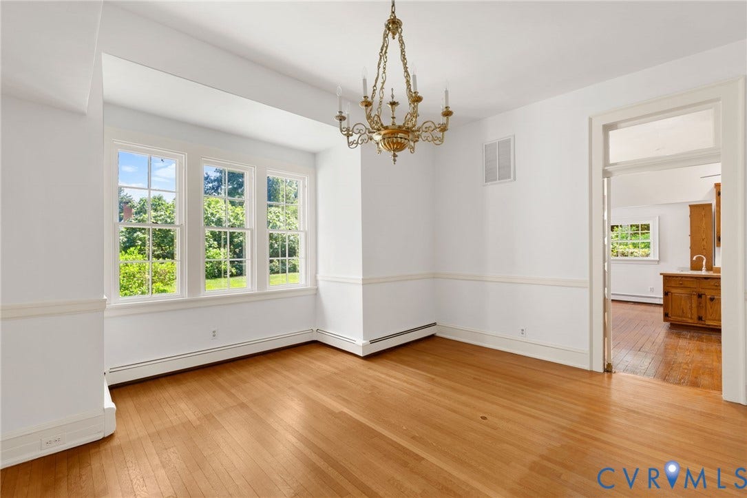 Hardwood flooring, classic chandelier, and multiple windows with exterior landscaping visible