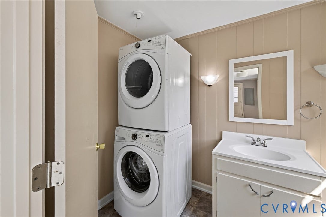 8415 Holly Hill Road, Henrico, VA 23229 Stacked washer and dryer, vanity with integrated sink, wall-mounted mirror, and wall sconces