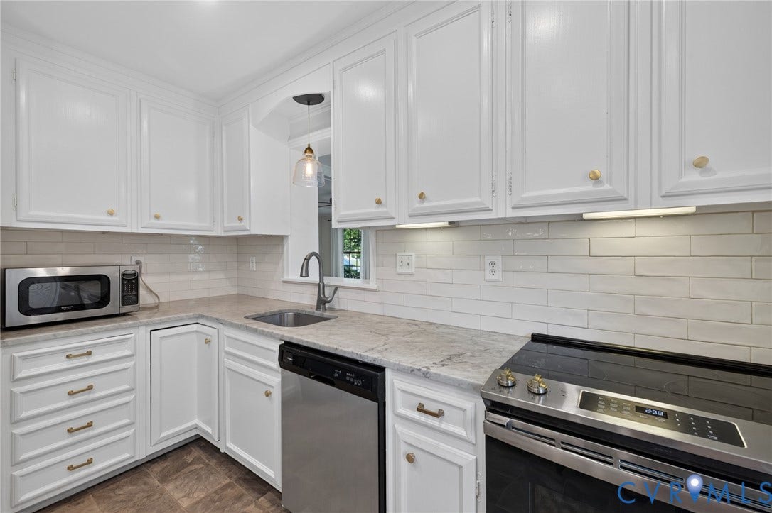 8415 Holly Hill Road, Henrico, VA 23229 White cabinetry with brass hardware, light-toned countertops, white subway tile backsplash, stainless steel appliances, and a stainless steel sink