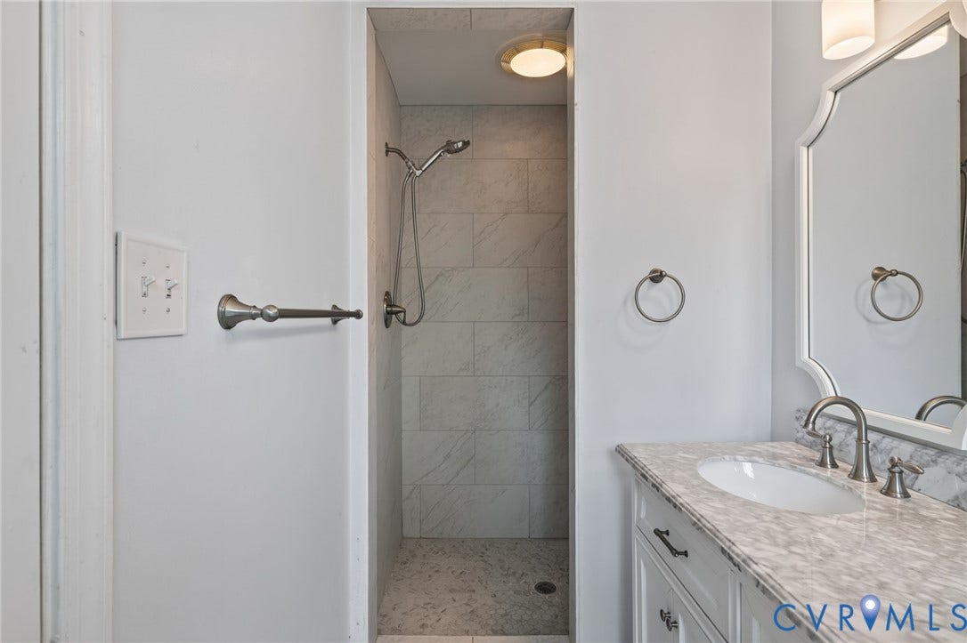 8415 Holly Hill Road, Henrico, VA 23229 Vanity with an oval undermount sink, stone countertop, and brushed nickel faucet