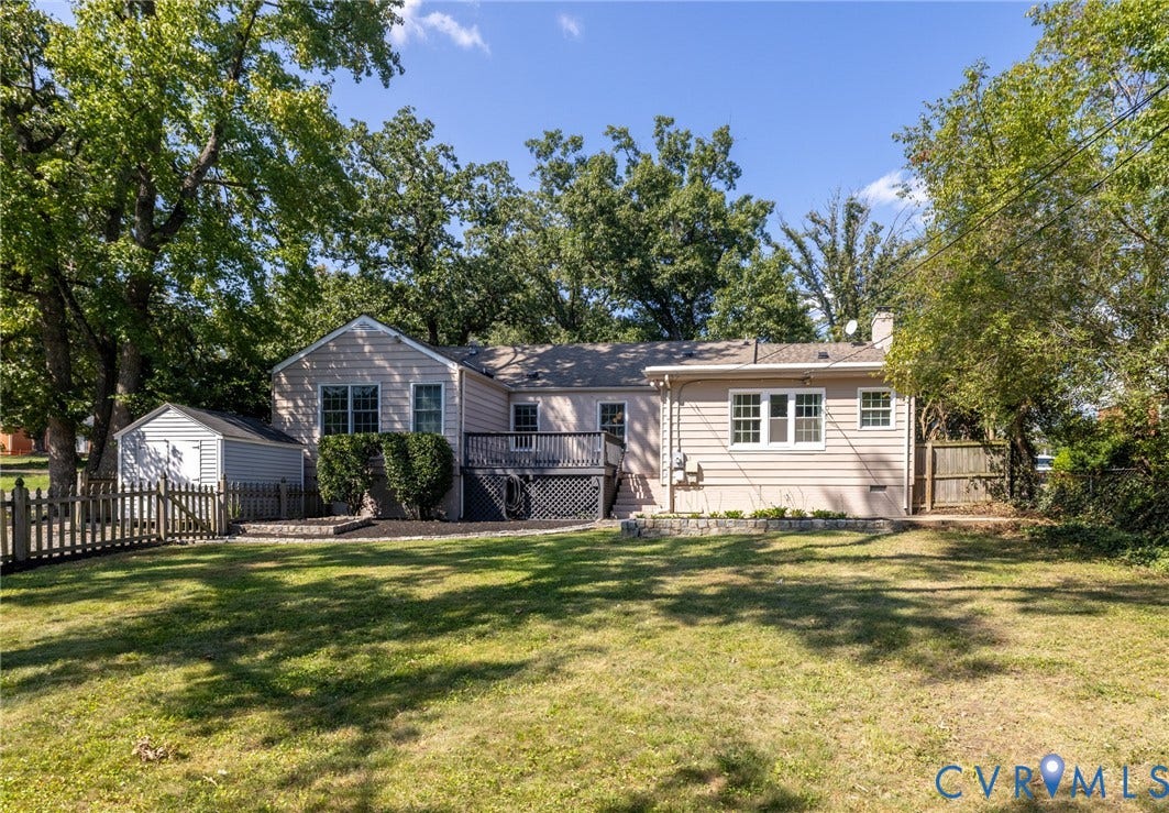 8415 Holly Hill Road, Henrico, VA 23229 Expansive backyard featuring a manicured lawn, picket fencing, mature trees, and a multi-level deck