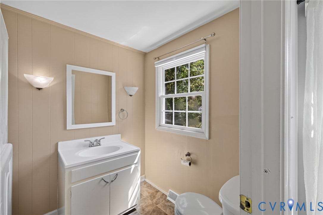 8415 Holly Hill Road, Henrico, VA 23229 White vanity with integrated sink, wall-mounted mirror, and sconce lighting