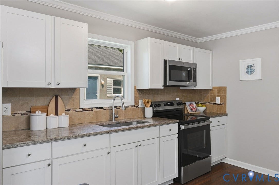 White shaker-style cabinetry, stainless steel appliances, speckled stone countertops, and tile backsplash