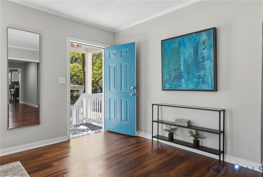 Hardwood-finish flooring, light gray wall color, white trim, and a blue paneled entry door