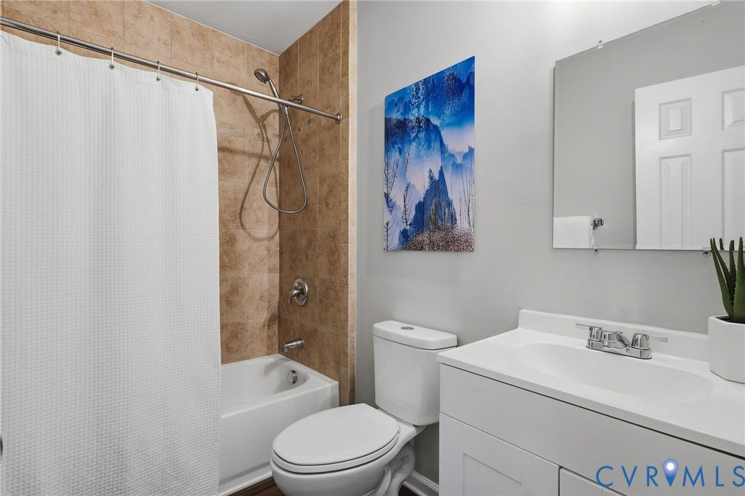 White vanity with an integrated sink and chrome faucet, rectangular wall-mounted mirror, and a white toilet