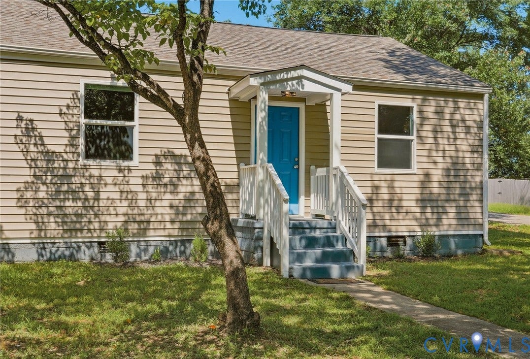 Exterior featuring light-colored horizontal siding, a covered porch with white railings, a vibrant blue front door, and a gray shingle roof